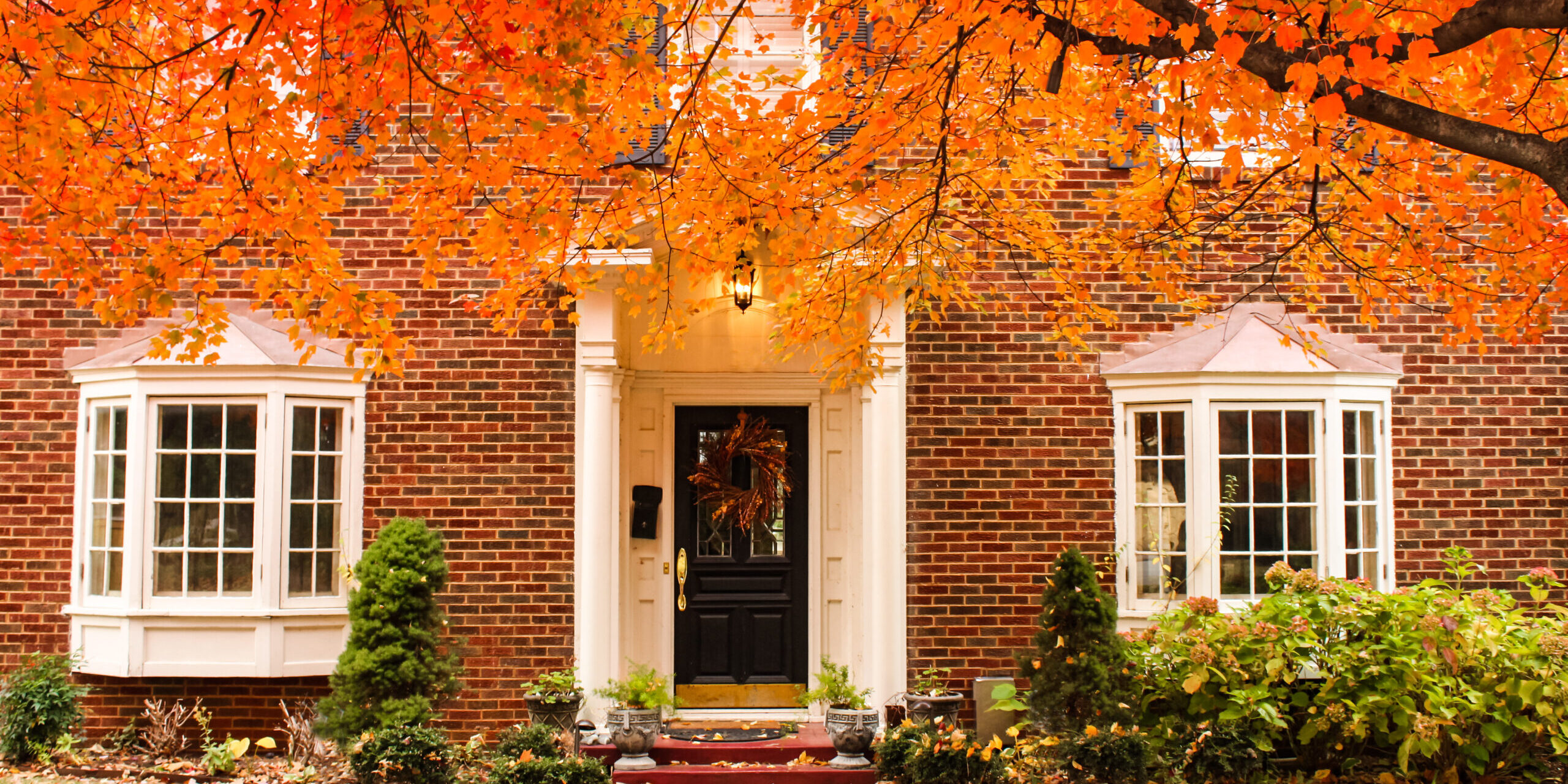 Red brick house entrance with seasonal wreath on door and porch