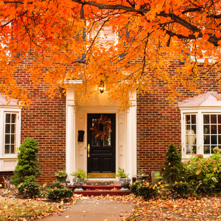 Red brick house entrance with seasonal wreath on door and porch